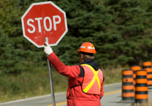 utility flagger holding stop sign on road in construction zone